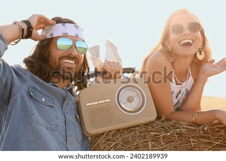Happy hippie couple with radio receiver in field