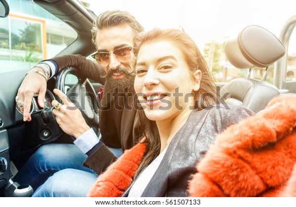 Happy\
hipster couple making selfie inside convertible cabriolet car -\
Young people having fun in road trip - Travel concept - Warm filter\
with sun flare in background - Focus on woman\
face