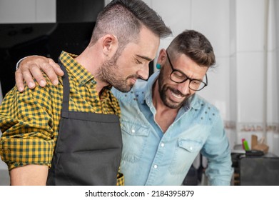 Happy Hipster Gay Couple In Love Standing In The Kitchen. They Are Cooking Dinner Together At Home. High Quality Photography