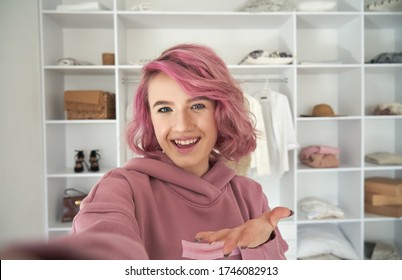 Happy hipster gen z teen girl fashion social media channel blogger stylist with pink hair wearing hoodie looking at camera recording vlog video tutorial in front of clothes wardrobe, face headshot. - Powered by Shutterstock