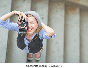 Happy hipster girl making photo with retro camera on city street - Shutterstock ID 159833045