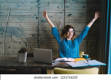 Happy hipster student rejoicing in success of training project holding hands up.Overjoyed young woman completed studying task during exam preparation sitting at desktop with laptop and textbook - Shutterstock ID 1251716233