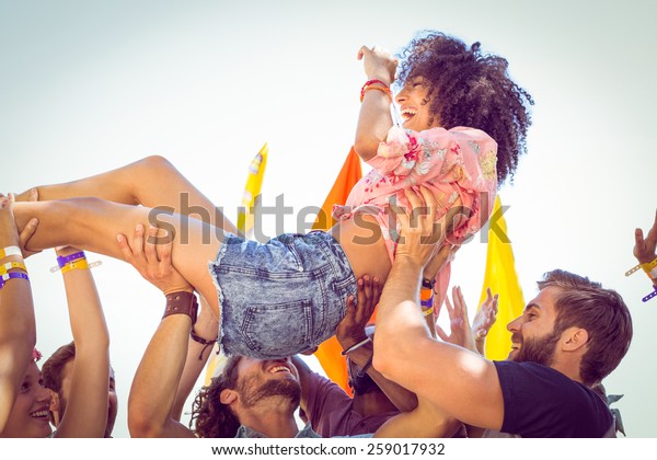 Happy\
hipster woman crowd surfing at a music\
festival
