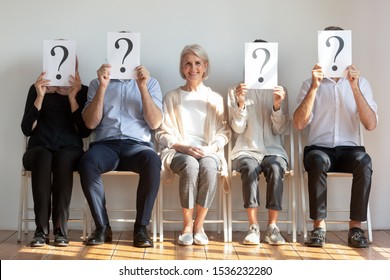 Happy Hired Employed Mature Old Businesswoman Professional Chosen Candidate Sitting Among People Hiding Faces Behind Questions Marks Waiting For Job Interview, Human Resource, Recruit Choice Concept