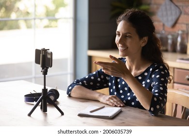 Happy Hispanic Blogger Girl Taking Video On Mobile Phone With Tripod, Speaking At Webcam. Employee, Applicant Using Smartphone For Remote Call, Job Interview. Tutor, Coach Holding Webinar From Home.