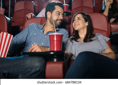 Happy Hispanic couple enjoying their date at the movie theater and looking in love