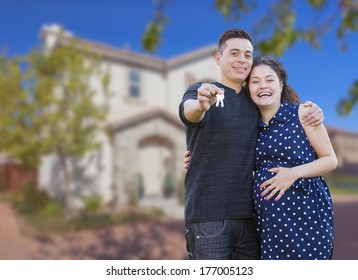 Happy Hispanic Couple In Front Of New Home Showing Off Their House Keys.