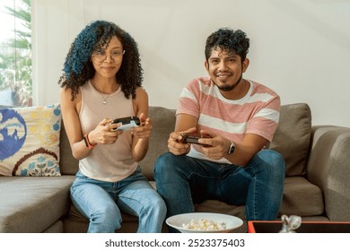 Happy Hispanic Family Enjoying Video Games Together, Young Couple Having Fun and Sharing Popcorn Indoors - Powered by Shutterstock