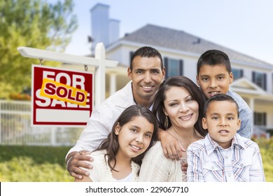 Happy Hispanic Family In Front Of Their New House And Sold Home For Sale Real Estate Sign.