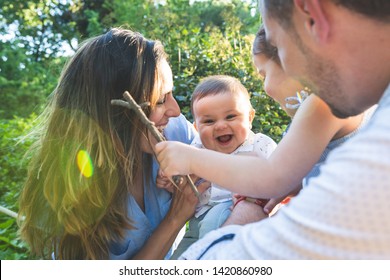 Happy Hispanic Family Having Fun Together Outdoors. Lovely Family Spending Time Together In The Park. Cute Spanish Couple Playing With Their Kids Outdoors. Family Concept.