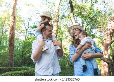 Happy Hispanic Family Having Fun Together Outdoors. Lovely Family Spending Time Together In The Park. Cute Spanish Couple Playing With Their Kids Outdoors. Family Concept.