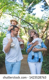 Happy Hispanic Family Having Fun Together Outdoors. Lovely Family Spending Time Together In The Park. Cute Spanish Couple Playing With Their Kids Outdoors. Family Concept.