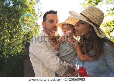 Happy Hispanic Family Having Fun Together Outdoors. Lovely Family Spending Time Together in the Park. Cute Spanish Couple Playing with Bubbles . Family Concept.
