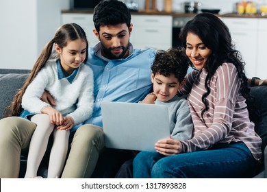 Happy Hispanic Family Looking At Laptop At Home