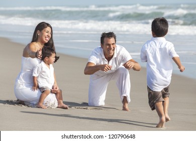 A Happy Hispanic Family Of Mother, Father And Two Children, Boy Sons, Playing And Having Fun In The Sand Of A Sunny Beach