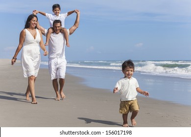 A Happy Hispanic Family Of Mother, Father Parents & Two Boy Son Children, Playng And Having Fun In The Waves Of A Sunny Beach