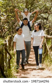 Happy Hispanic Family Walking In The Natural Park - Young Parents With Their Children In The Park -latin Family