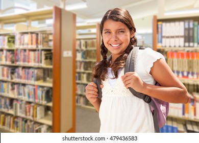 Happy Hispanic Girl Student Wearing Backpack Walking In The Library.