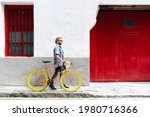 Happy hispanic man carrying a vintage bicycle at the old town of a city. Sustainable tourism concept.