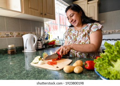 Happy Hispanic Mom Cooking Healthy Food - Mature Woman Cutting Fresh Vegetables In Her Kitchen - Woman Making Healthy Salad