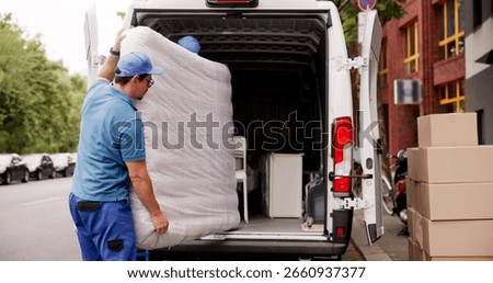 The Happy Hispanic Movers Loading Mattresses Into Delivery Truck Together.