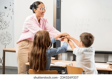 Happy hispanic teacher and children put hands on each other and celebrate excellent completion of assignments. Hand on hand Like a game and a gesture of unity and solidarity. Fun creative learning - Powered by Shutterstock