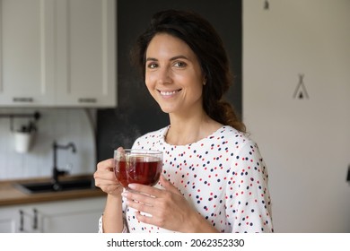 Happy Hispanic Woman Drinking Yellow Tea At Home, Holding Big Glass Mug, Looking At Camera And Smiling. Female Homeowner Taking Break, Enjoying Hot Morning Aromatic Beverage In Kitchen