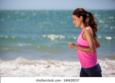 Happy Hispanic Young Woman Jogging At The Beach On A Sunny Day