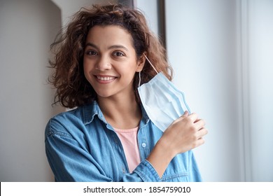 Happy Hispanic young woman takes off protective mask and looking at camera indoors while corona virus pandemic. Quarantine, and social distance concept.  - Shutterstock ID 1854759010