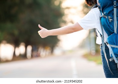 happy hitchhiker asian woman thumb up for car transportation for backpack travel for relax in long vacation in holiday