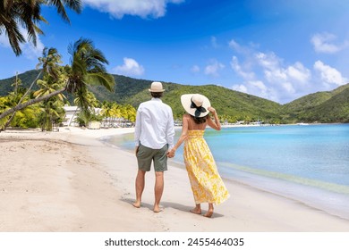 Happy holiday couple with sunhats walks down a tropical beach surrounded by rain forest in the Caribbean, Antigua island - Powered by Shutterstock