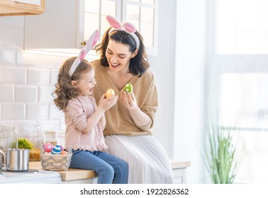 Happy holiday! A mother and her daughter are painting eggs. Family preparing for Easter. Cute little child girl is wearing bunny ears. - Powered by Shutterstock