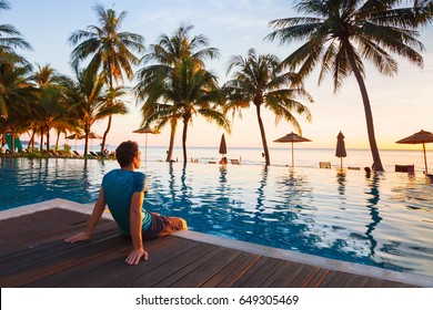 Happy Holidays In Beautiful Beach Hotel At Sunset, Man Sitting Near Swimming Pool And Relaxing