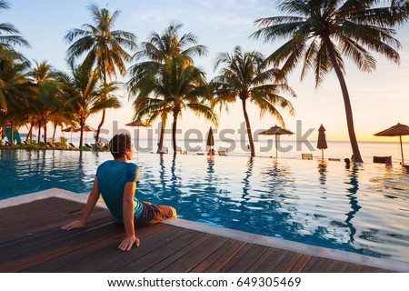 happy holidays in beautiful beach hotel at sunset, man sitting near swimming pool and relaxing
