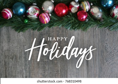 Happy Holidays Calligraphy With Festive Colorful Holiday Christmas Ornament Border Over Garland And Wood Background