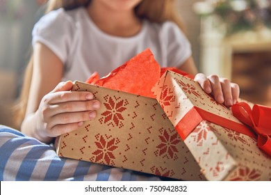 Happy Holidays! Cute Little Child Opening Gift At Christmas. Close Up. 