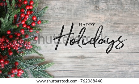 Happy Holidays Text with Holiday Evergreen Branches and Berries in Corner Over Rustic Wooden Background