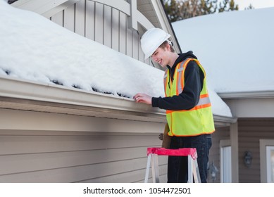 Happy Home Inspector On A Ladder While Holding A Clipboard During Winter. 