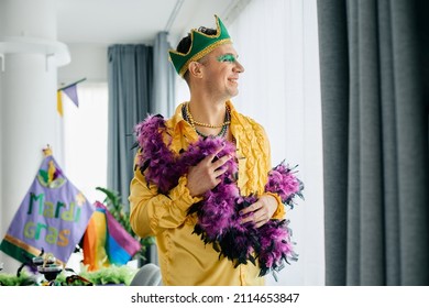 Happy Homosexual Man In Mardi Gras Costume Looking Through The Window At Home.