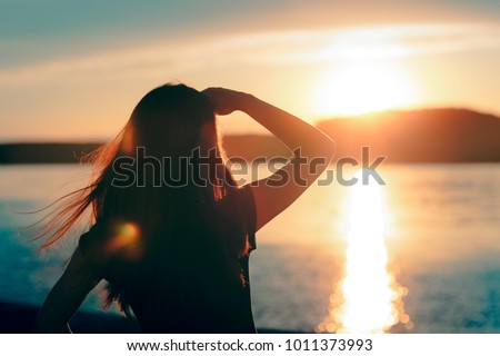 Happy Hopeful Woman Looking at the Sunset by the Sea. Silhouette of a dreamer girl looking hopeful at the horizon
