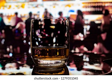 Happy Hour At Bar Whiskey Scotch Neat On Reflective Wood Surface With Many People Silhouetted In Background.