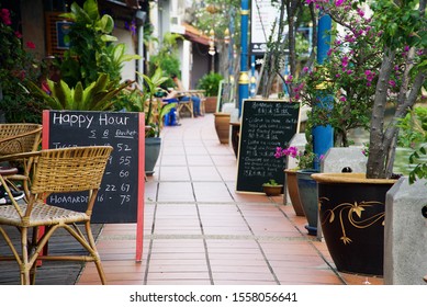 Happy Hour Written On The Board And Placed Outside Of The Shop With Background Bokeh.