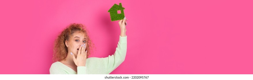 Happy House Buyer. A Young Girl Holds A Model Of A Green House In Her Hands. The Concept Of Green Energy, Ecology.