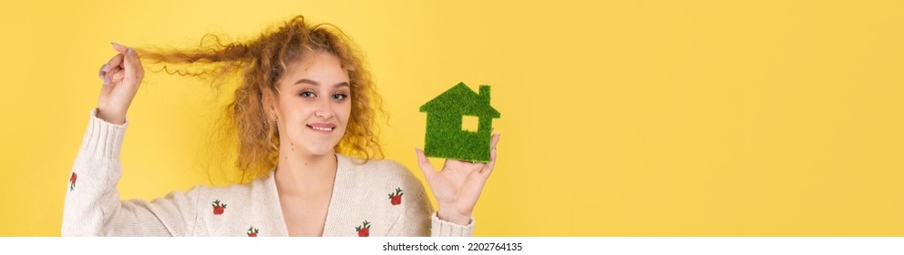 Happy House Buyer. A Young Girl Holds A Model Of A Green House In Her Hands. The Concept Of Green Energy, Ecology.