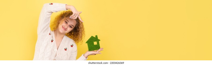 Happy House Buyer. A Young Girl Holds A Model Of A Green House In Her Hands. The Concept Of Green Energy, Ecology.