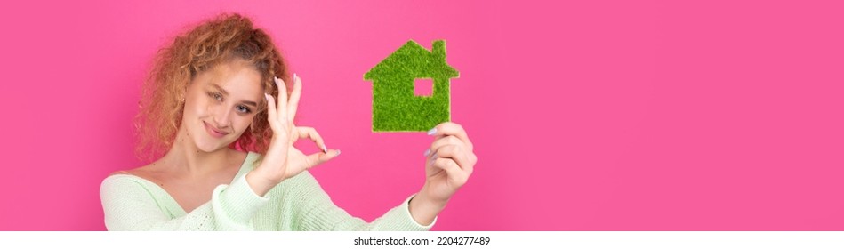 Happy House Buyer. A Young Girl Holds A Model Of A Green House In Her Hands. The Concept Of Green Energy, Ecology.