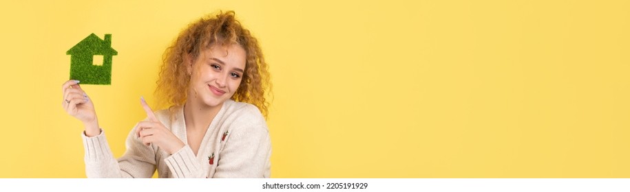 Happy House Buyer. A Young Girl Holds A Model Of A Green House In Her Hands. The Concept Of Green Energy, Ecology.