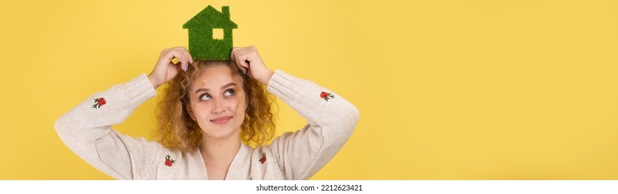 Happy House Buyer. A Young Girl Holds A Model Of A Green House In Her Hands. The Concept Of Green Energy, Ecology.