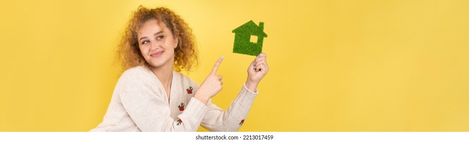 Happy House Buyer. A Young Girl Holds A Model Of A Green House In Her Hands. The Concept Of Green Energy, Ecology.