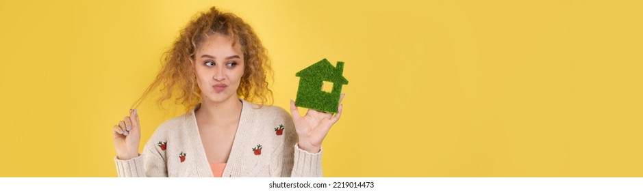 Happy House Buyer. A Young Girl Holds A Model Of A Green House In Her Hands. The Concept Of Green Energy, Ecology.